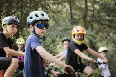 Młodzi rowerzyści w kaskach i goglach czekają na start treningu